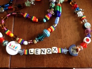 You can see the glass fish bead (aqua) above her name. Also note the face of a girl to the right of her name. That represents her hair loss. 